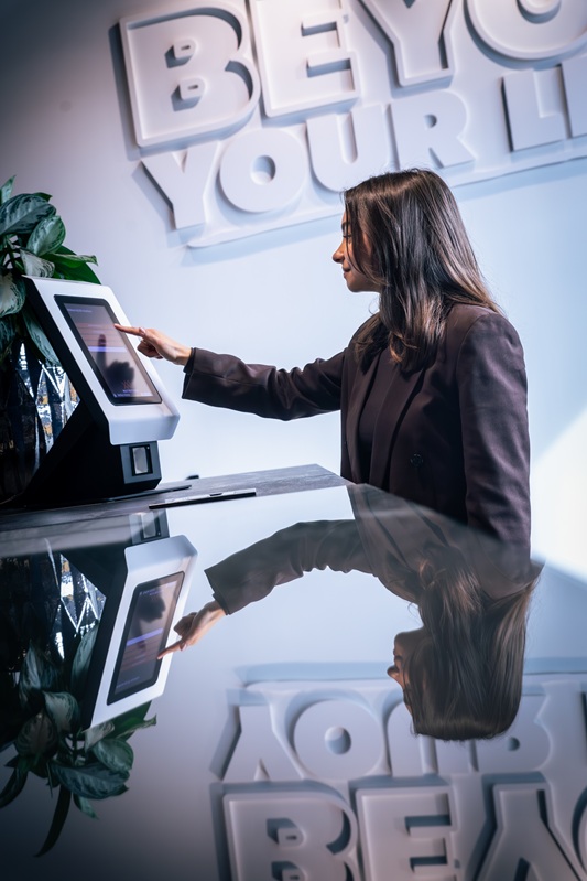Vrouw meld zich aan bij digitale bezoekersregistratie aanmeldzuil