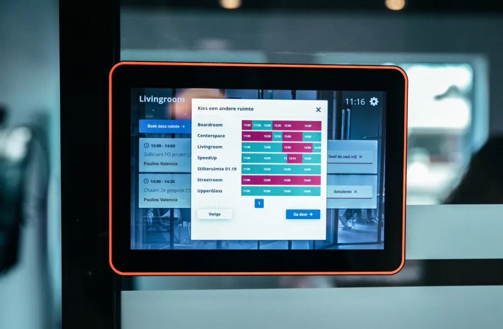 Een tablet toont een ruimtereserveringsscherm met opties voor het kiezen en reserveren van vergaderruimtes.