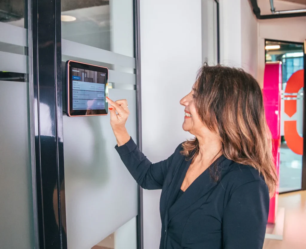 Vrouw bedient zaaldisplay voor room booking bij de ruimte